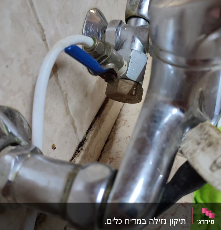 ברז מתכת עם צינור לבן ושסתום כחול
